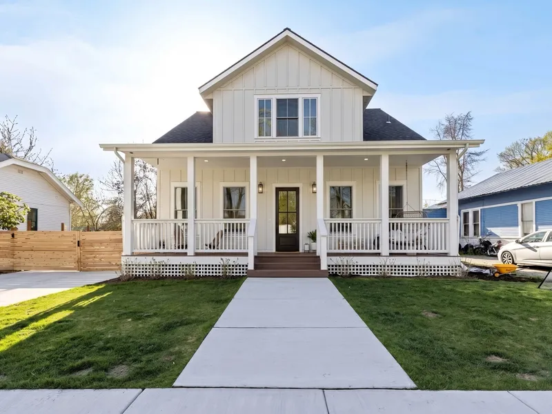 White farmhouse-style craftsman home with a wraparound porch on a spring lawn in Coeur d'Alene's Garden District