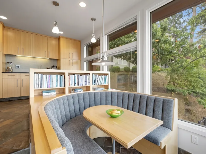 Built-in breakfast nook with a curved upholstered bench and warm wood cabinetry beside a bright window